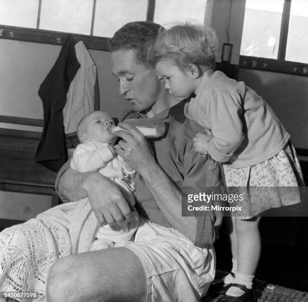 Plymouth Argyle footballer Neil Dougall feeds his children in the dressing room at his club, November 1953.