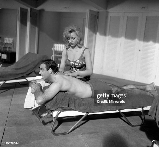 Sean Connery on the set of the James Bond movie Goldfinger being shot at Pinewood studios is given a massage by Margaret Nolan. April 1964.