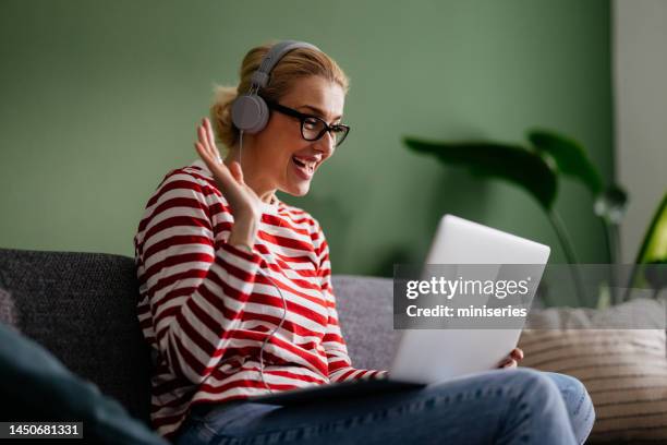 donna d'affari sorridente saluta i colleghi in una videochiamata a casa - businesswoman blond looking left foto e immagini stock