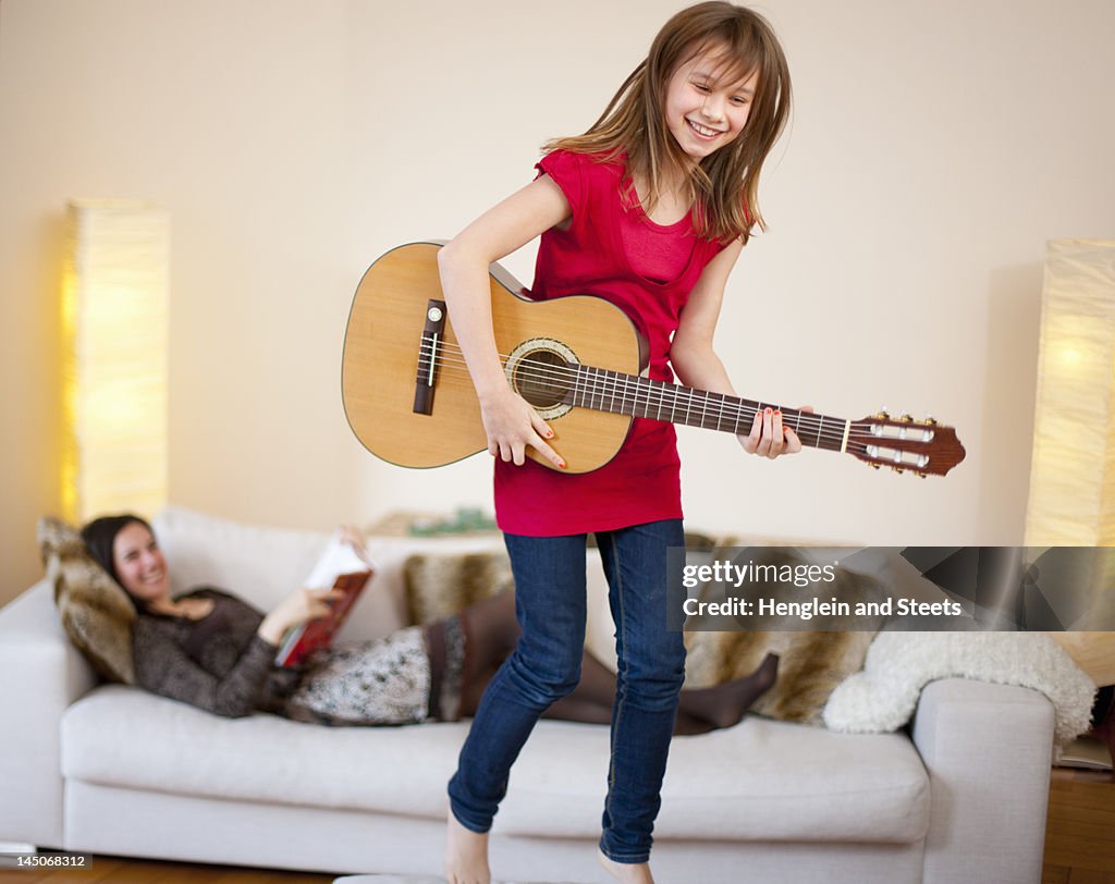 Girl playing guitar in living room