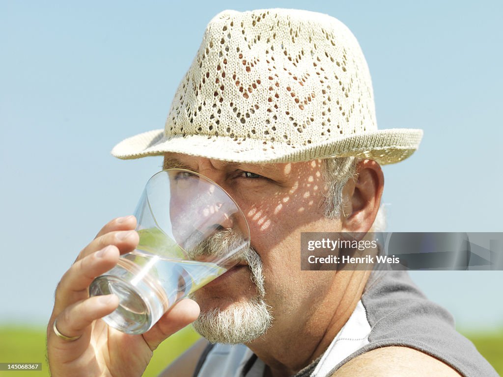 Older man drinking water outdoors