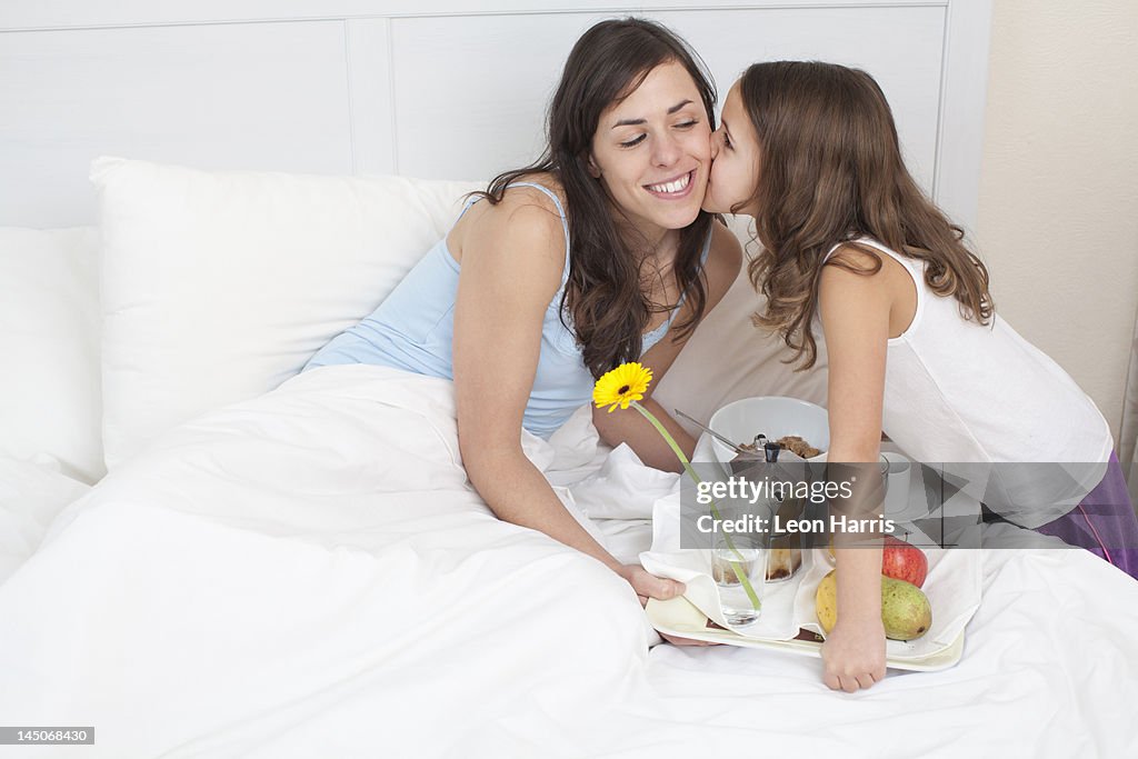 Girl bringing mother breakfast in bed