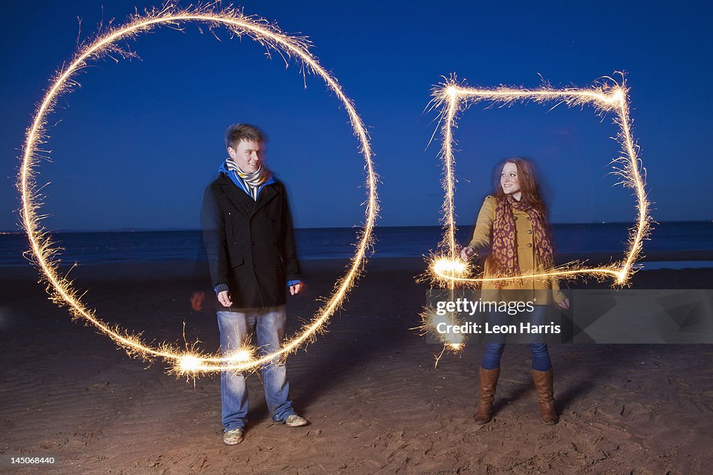 Couple playing with sparklers on beach