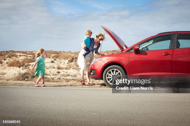 mother examining broken down car - vehicle breakdown stock pictures, royalty-free photos & images