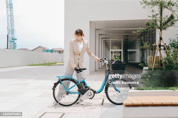 eine vielbeschäftigte asiatische geschäftsfrau parkt ein gemeinsames fahrrad - elektro fahrrad stock-fotos und bilder