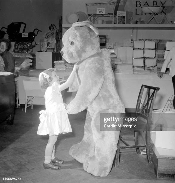 Rosemary Allerton tickles the huge teddy bear under the chin in the toy department section of Lewis Ltd in LeedsDecember 1953.