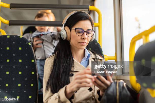 woman whit headphones using mobile phone in bus - people on buses stockfoto's en -beelden