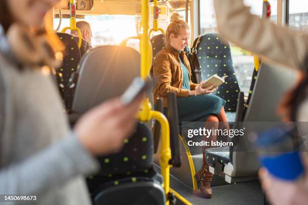 donna che legge un libro mentre viaggia in autobus - motorized vehicle riding foto e immagini stock