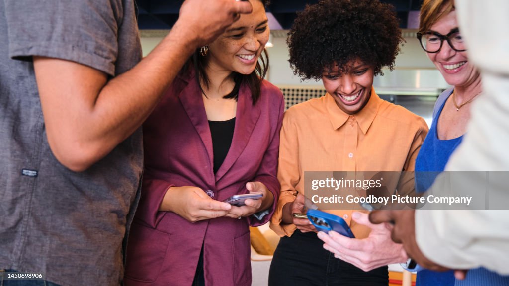 Smiling businesspeople checking their phones during a break at work