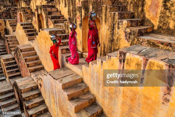 farben indiens - indische frauen tragen wasser aus dem stufenbrunnen in der nähe von jaipur - jaipur stock-fotos und bilder