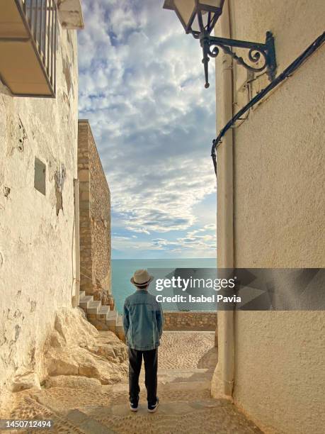 boy at little street situated in the old town of peniscola, castellon, spain; a medieval tourist town located into the mediterranean sea. - village boy foto e immagini stock