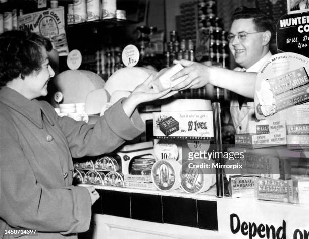 City grocery assistant, Mr William Wanup, serves a customer on the first day of the de-rationing of butter, 14 years after it began during the Second...