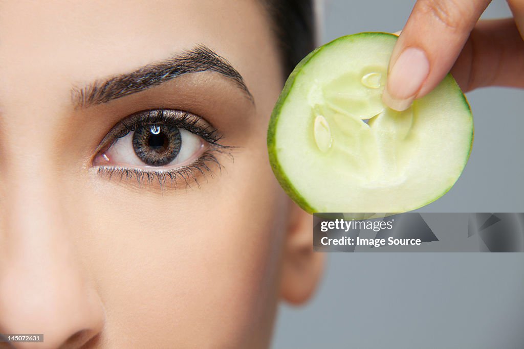 Woman with a cucumber next to her eye