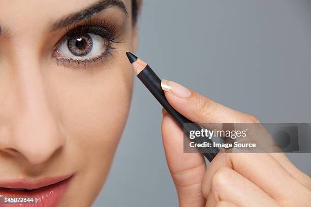 beautiful woman applying eyeliner - lápiz de ojos fotografías e imágenes de stock