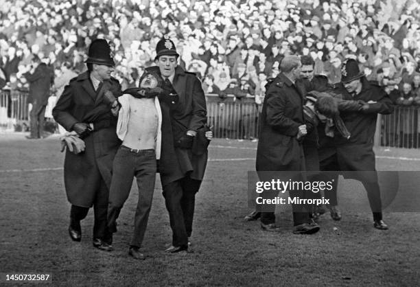 Policemen drag two fans from the field during the match between Swansea Town and Arsenal at the Vetch Field. 17th February 1968.