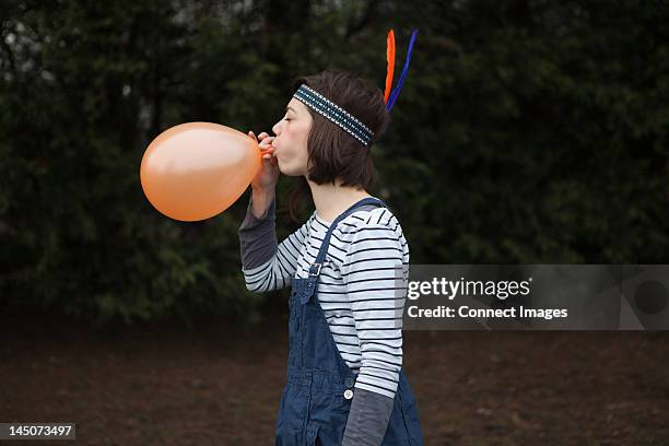 young woman in headdress, blowing up a balloon - blowing up balloon bildbanksfoton och bilder