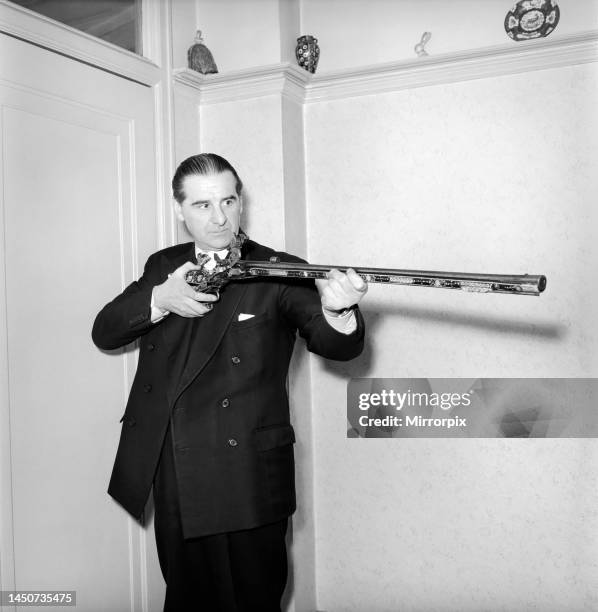 Pip Roberts a collector of antique firearms, seen here demonstrating a flintlock pistol, circa 1957.
