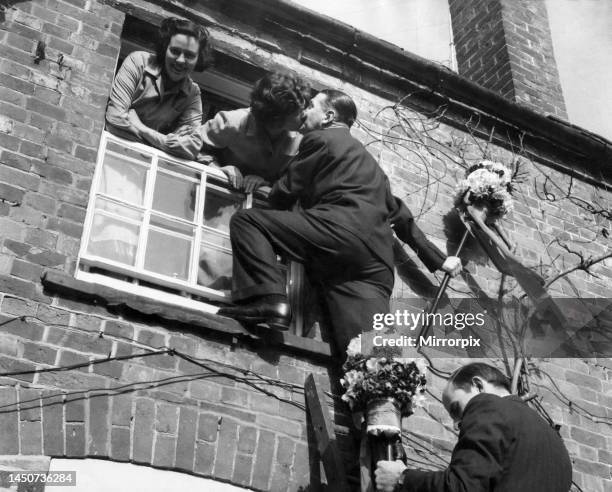 The tutti-men climb a ladder to get the traditional kiss the window during the Hock-tide festival at Hungerford. April 1955.