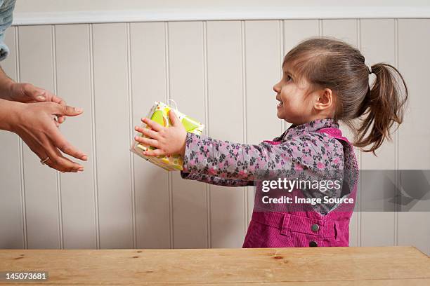 little girl giving a gift to adult - child giving gift foto e immagini stock