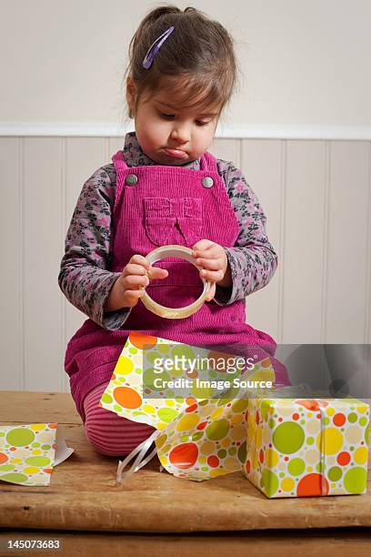 little girl frowning as she wraps a gift - sad birthday stock pictures, royalty-free photos & images