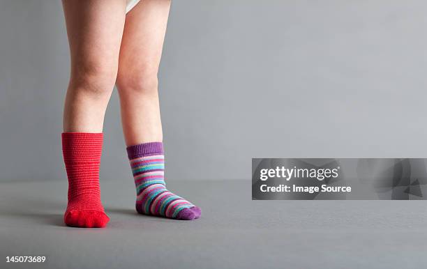 child wearing one red sock and one striped sock - twee objecten stockfoto's en -beelden