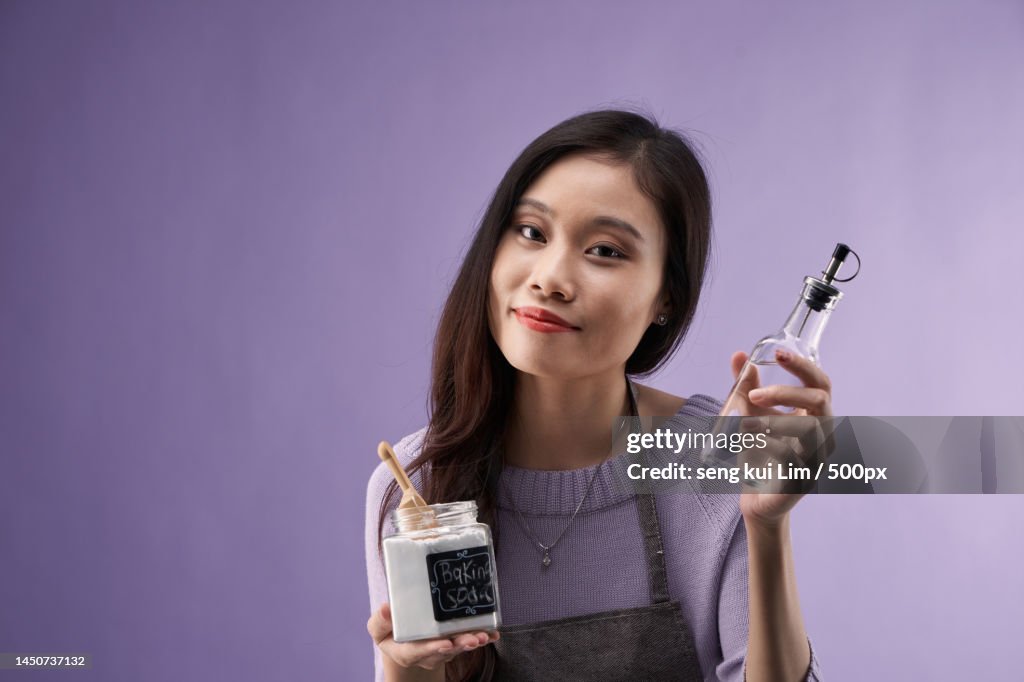 Chinese women holdingjar of baking soda and bottle of vinegar,Malaysia