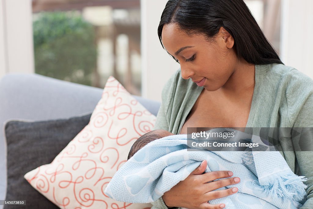 Young woman holding baby son in blanket