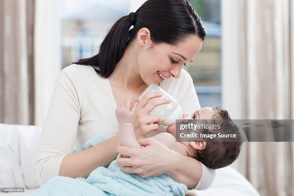 Mother bottle feeding baby boy