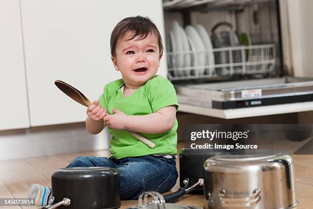 upset baby on floor with saucepans and wooden spoon - holding saucepan stock pictures, royalty-free photos & images