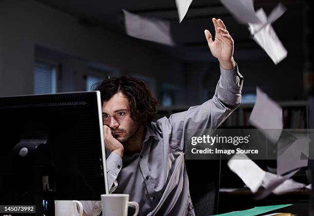 office worker working late, throwing paper in the air - verdruss stock-fotos und bilder