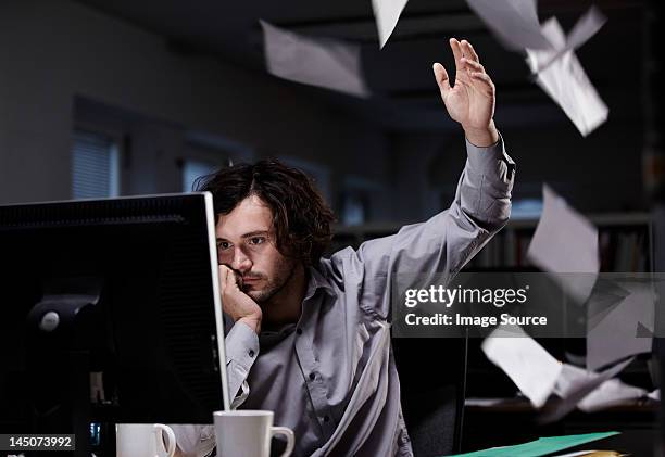 office worker working late, throwing paper in the air - irritatie stockfoto's en -beelden