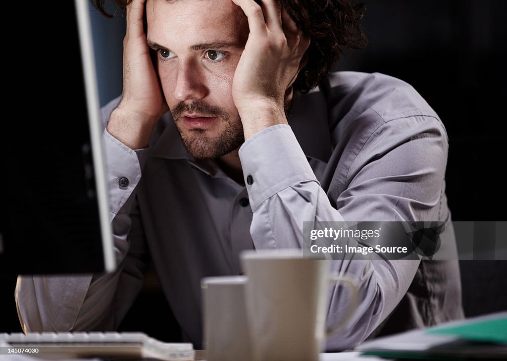 Stressed young man, working late