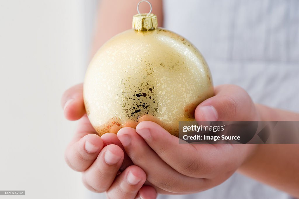 Girl holding a gold christmas bauble