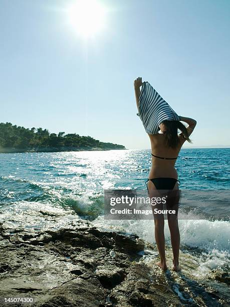 young woman taking off t-shirt by the sea - camisa a rayas fotografías e imágenes de stock