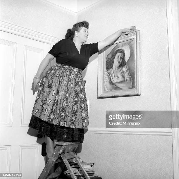 Woman dusting the picture frame . Circa 1954.