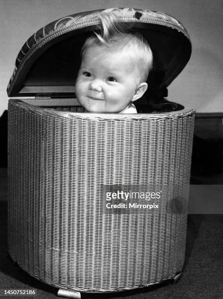 Month old baby girl Julie sitting in a straw basket. 8th November 1953.