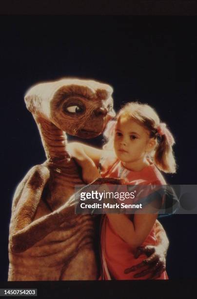 Drew Barrymore poses with E.T. At Carlo Rimbaldi studio in April, 1982 in Los Angeles, California.