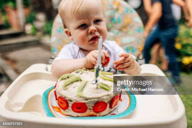 an infant turns one and enjoys a healthy cake at his birthday party. - 1st birthday stock-fotos und bilder