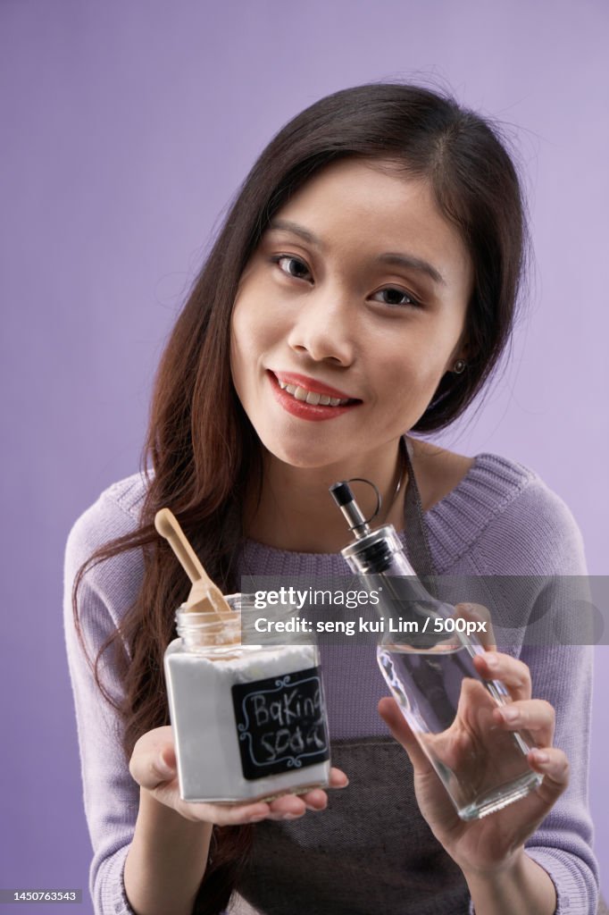 Chinese women holdingjar of baking soda and bottle of vinegar,Malaysia