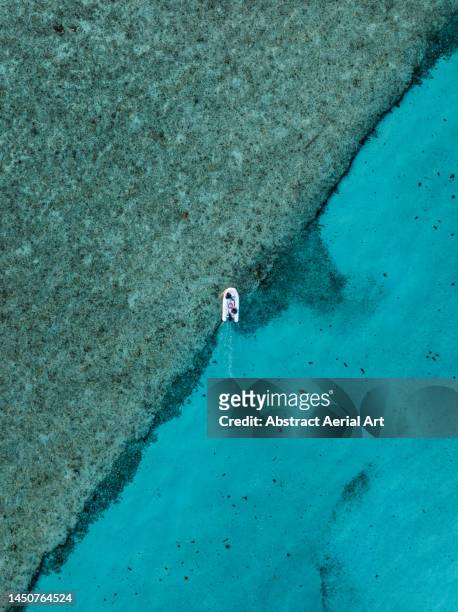 sailing dinghy crossing the edge of a sea channel in the ocean photographed from a drone, nassau, new providence, bahamas - inlet stock pictures, royalty-free photos & images