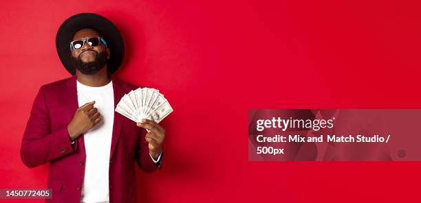 sassy and cool african american man in sunglasses and hat,pointing at - sassy shades foto e immagini stock