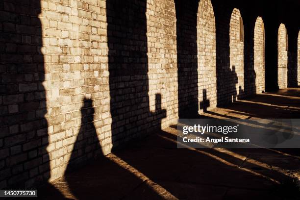 sunlight through cypriot archways. silhouette of graveyard crosses on brick wall during sunset - crucifix stock pictures, royalty-free photos & images