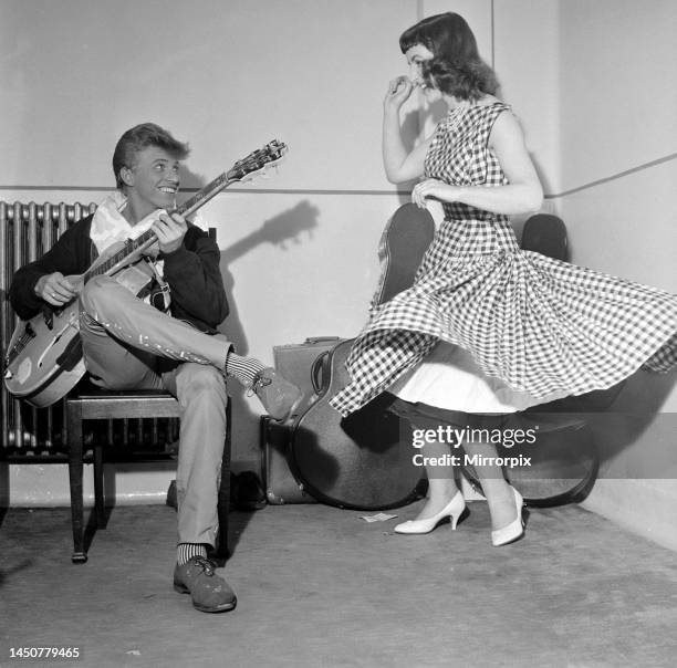 Rock and Roll singer Tommy Steele plays his guitar as girl dances for him, June 1957.