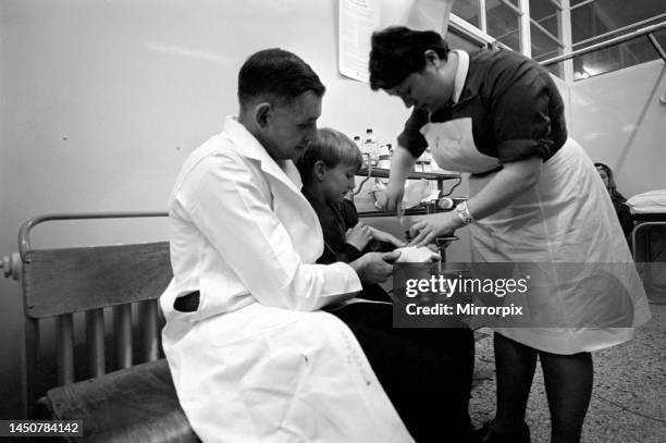 Young boy with an injured hand gets treatment from a nurse at the hospital. November 1969.