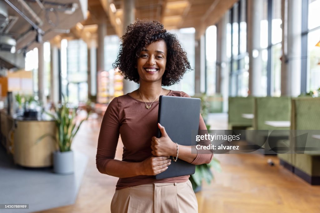 Portrait of happy African businesswoman holding digital tablet in the office