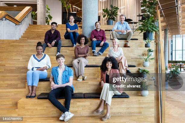 階段に一緒に座っている多民族ビジネスチームのポートレート - 宣伝イベント ストックフォトと画像