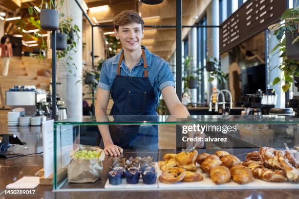 cafe worker serving pastry at counter - vitrinekast stockfoto's en -beelden