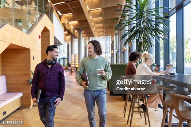 two men walking through office cafe and talking - incidental people stock pictures, royalty-free photos & images