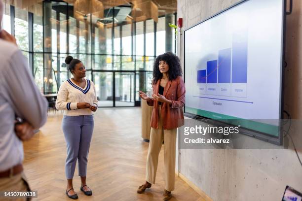 young woman giving presentation to colleagues at a modern office - germany team presentation stockfoto's en -beelden