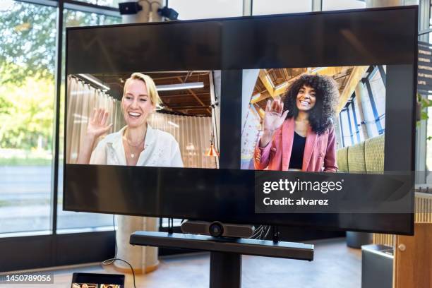 businesswomen seen on television screen waving hands during video conference - lcd tv stock pictures, royalty-free photos & images